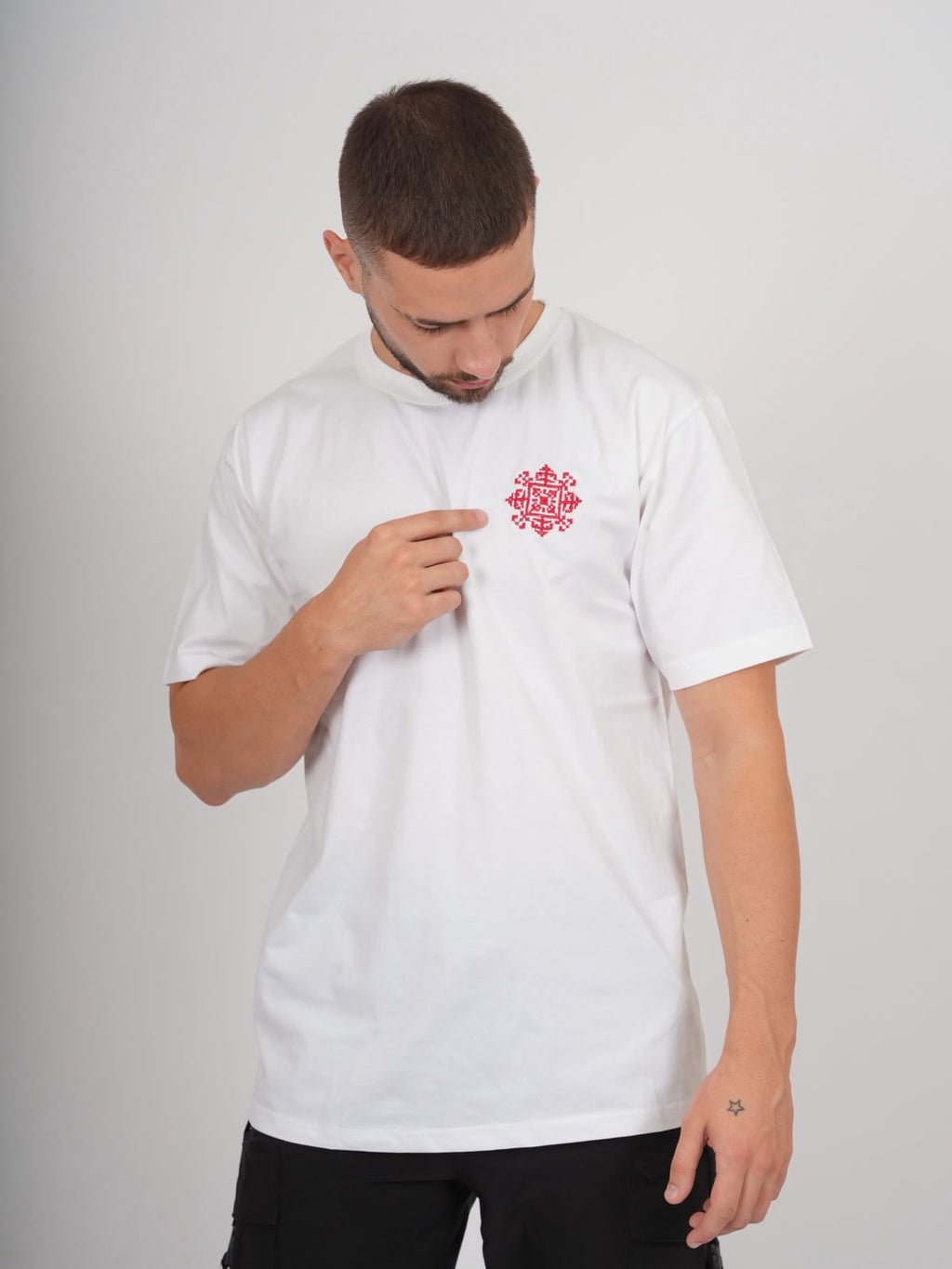 Männliches Model trägt weißes Jerusalem Tatreez T-Shirt mit roter Stickerei auf der linken Brust
