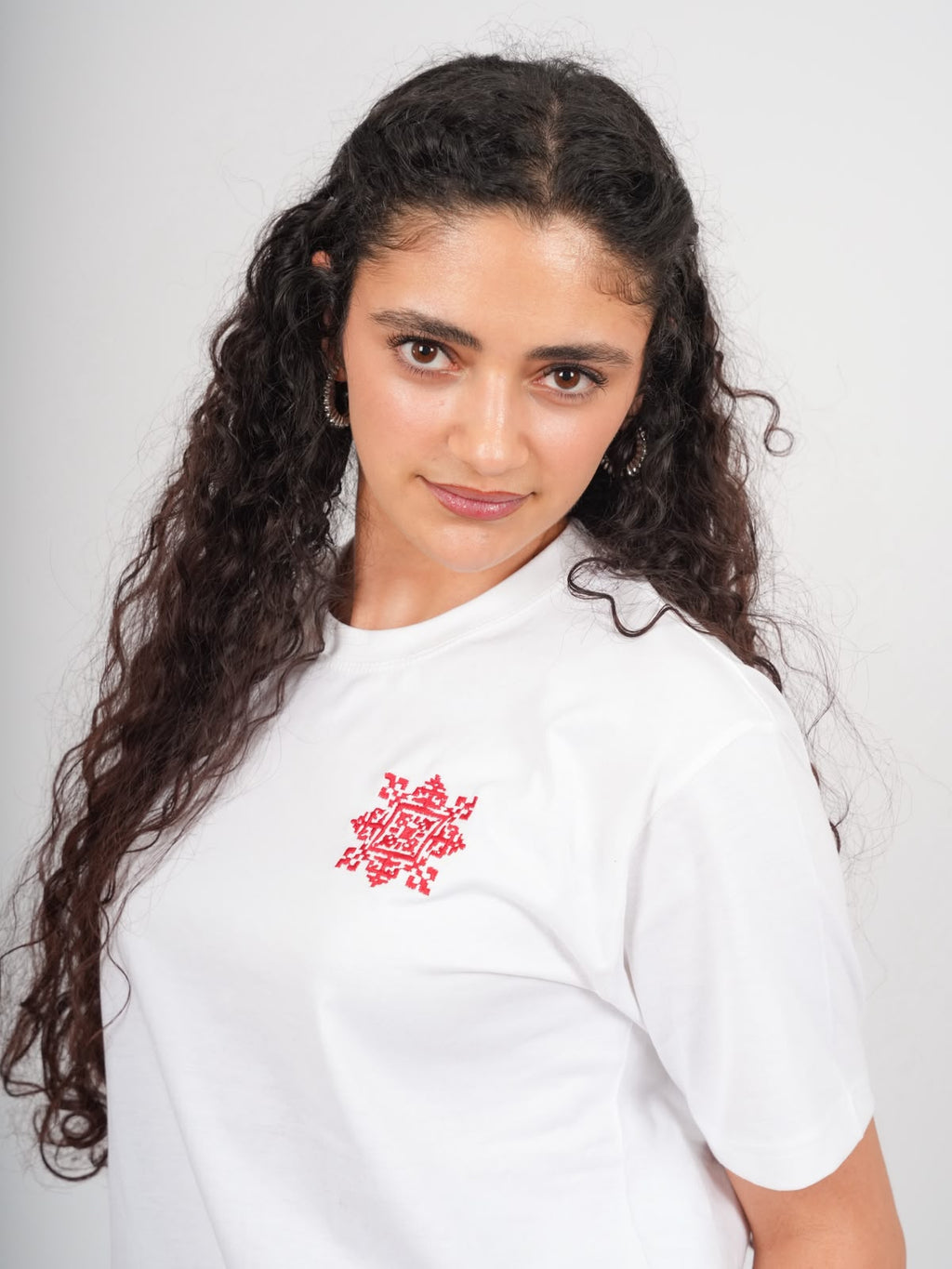 Nahaufnahme eines weißen Tatreez T-Shirts mit roter handgestickter Sur Al Quds Stickerei

5
